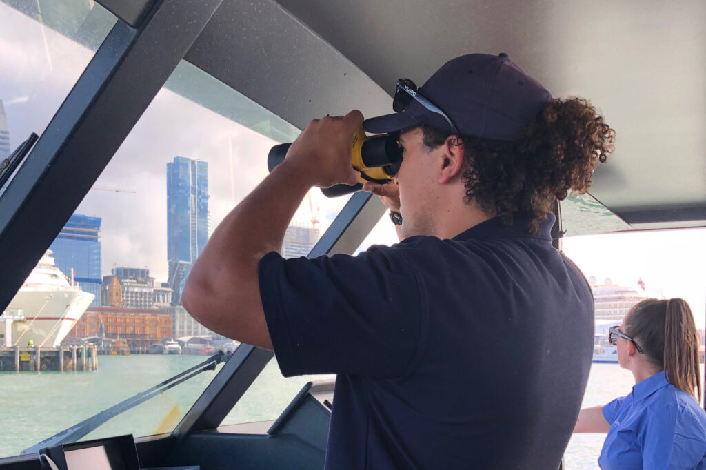 A person is looking through binoculars on a ship
