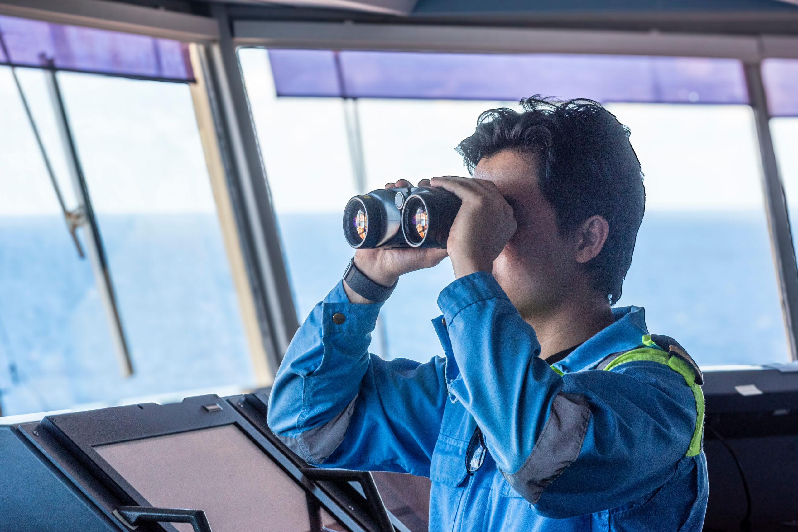 A deck officer, looking through binoculars